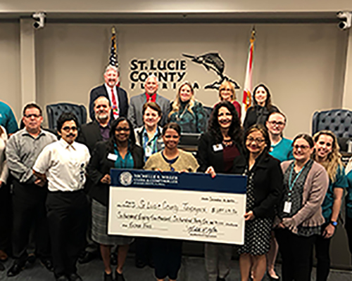 Clerk Michelle Miller presents a check to the St. Lucie County Board of County Commissioners with the Clerk Finance Department.