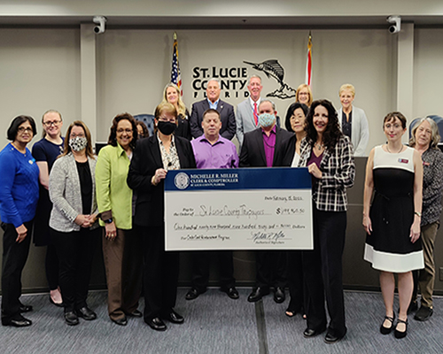 Clerk Michelle Miller presents a check to the St. Lucie County Board of County Commissioners with the Clerk Finance Department.